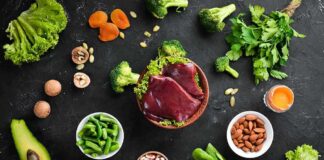 Raw liver with assorted healthy foods on dark surface