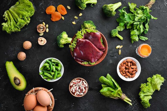 Raw liver with assorted healthy foods on dark surface