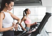 Woman on treadmill checking smartwatch in gym