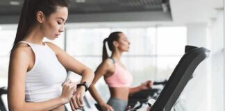 Woman on treadmill checking smartwatch in gym