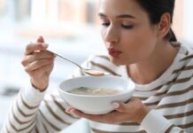 Woman blowing on a spoonful of hot soup