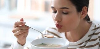 Woman blowing on a spoonful of hot soup