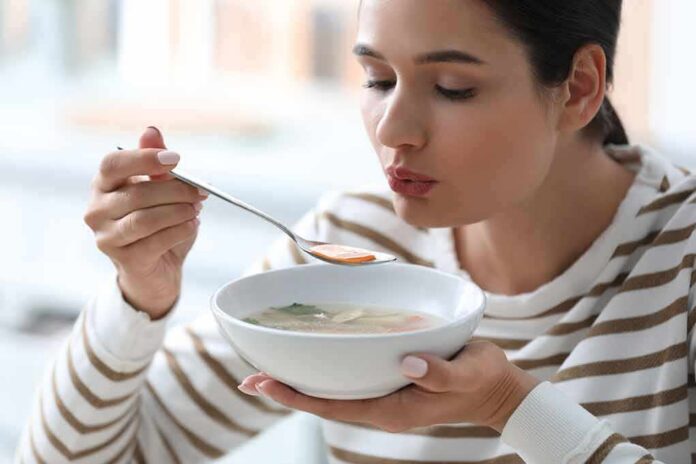 shutterstock_1595826901 Woman blowing on a spoonful of hot soup