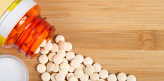 Spilled white pills from a prescription bottle on a wooden surface