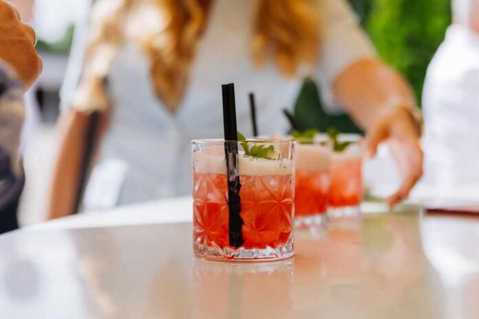 Close-up of cocktails on a table with a person reaching for one