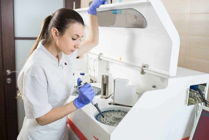Lab technician using an analyzer with a pipette
