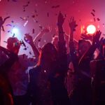 Group of people dancing under confetti and colorful lights