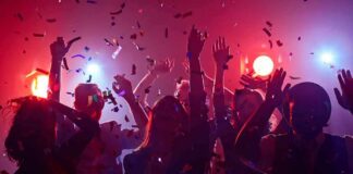 Group of people dancing under confetti and colorful lights