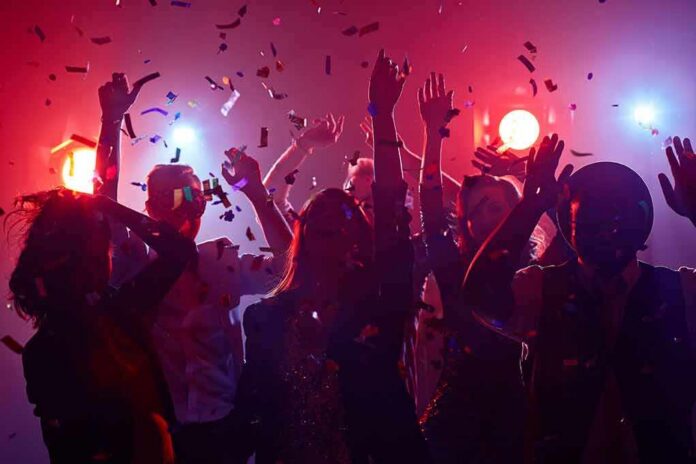 shutterstock_351380480-1 Group of people dancing under confetti and colorful lights