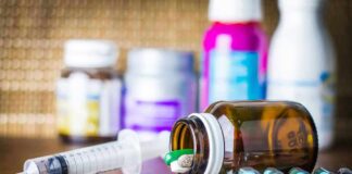 Medicine pills and syringe on table with brown bottle