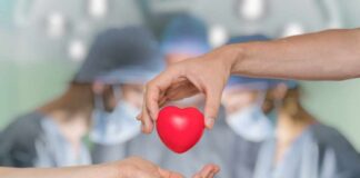Two hands exchanging a red heart symbol in a surgical setting