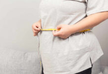 Person measuring their waist with a tape measure