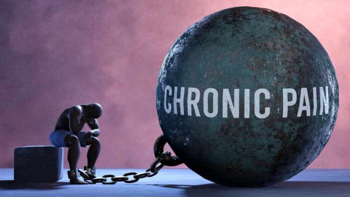Chronic,Pain,-,A,Gigantic,And,Unmovable,Weight,Chained,To A figure representing chronic pain, sitting beside a large ball labeled 'CHRONIC PAIN' chained to their body