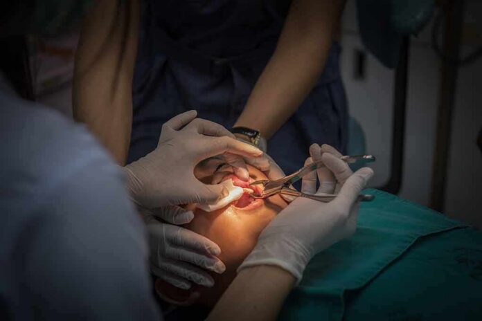 Dental surgeons perform oral procedure with instruments