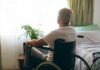 older man in a wheelchair looking out a bright window