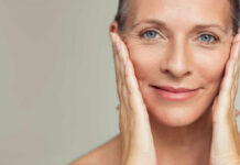Sunscreen Myths That Could Cost Your Face Close-up portrait of a smiling woman gently holding her face