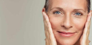Close-up portrait of a smiling woman gently holding her face