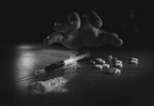 Substance Use Recovery: Boring Habits For Lasting Remission A hand reaching for pills next to a syringe and powder on a table