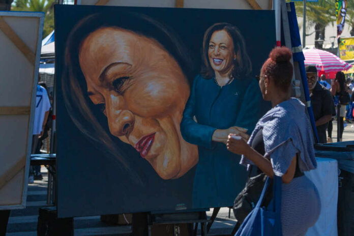 9a3727d6-ff70-4c52-bc15-2dd3fe515569_shutterstock_2533160425 A woman admires a large portrait of a smiling female figure at an outdoor event