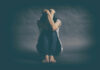 Why Depression Is More Prevalent Among Women A person sitting on the floor with their arms wrapped around their knees, conveying a sense of distress