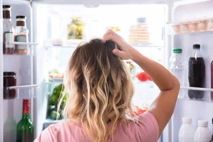 shutterstock_1005702643 Person looking into an open refrigerator