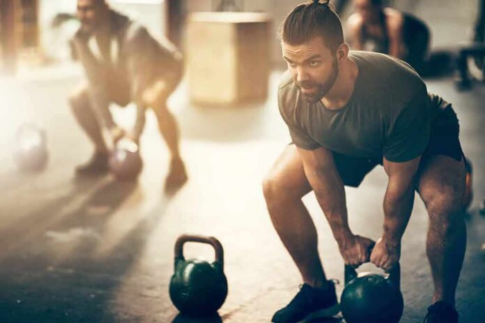 shutterstock_1043370892-1 Man lifting a kettlebell in a gym