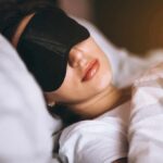 Woman sleeping with a black eye mask in bed