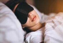 Woman sleeping with a black eye mask in bed