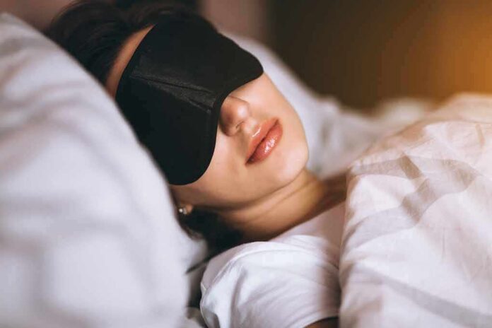 Woman sleeping with a black eye mask in bed