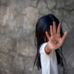 child with hand raised showing an X on palm