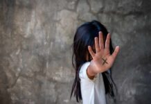 child with hand raised showing an X on palm