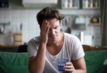 Man with headache holding a glass of water