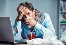 Sick man at desk blowing his nose
