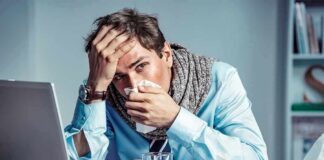 Sick man at desk blowing his nose