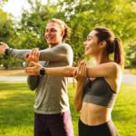Two people stretching arms in a sunny park