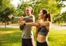Two people stretching arms in a sunny park