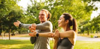 Two people stretching arms in a sunny park