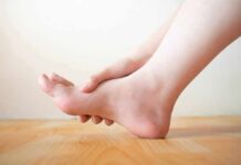 Common mistake that makes aging joints hurt more Hand holding the arch of a bare foot on a wooden floor