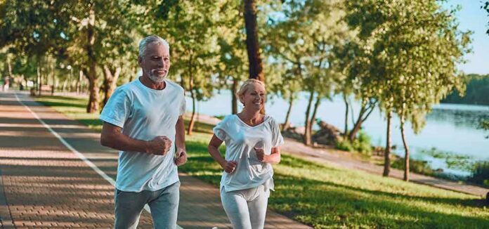 Older couple jogging on a lakeside path