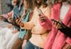 group of people using smartphones while standing in a row