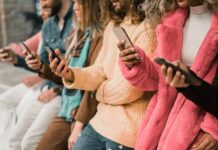 group of people using smartphones while standing in a row