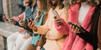 group of people using smartphones while standing in a row
