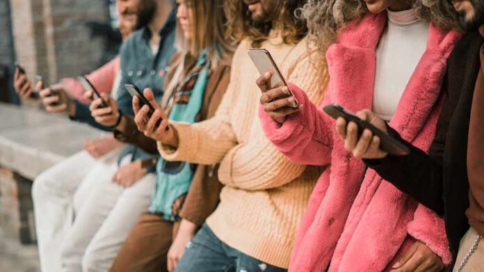 group of people using smartphones while standing in a row