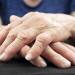 Elderly hands resting and crossed on a dark surface