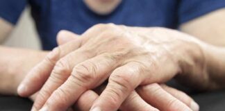 Elderly hands resting and crossed on a dark surface