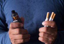 Hands holding a vape device and cigarettes