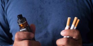 Hands holding a vape device and cigarettes