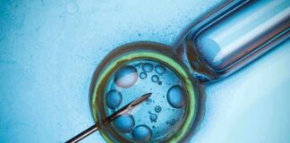Close-up of a needle and vial with liquid droplets on a blue background