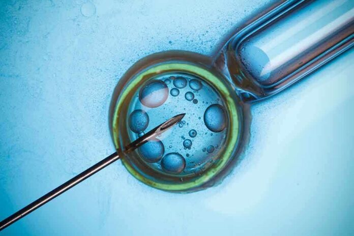 shutterstock_224787499 Close-up of a needle and vial with liquid droplets on a blue background
