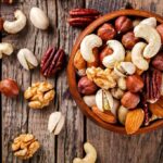 Assorted mixed nuts in a wooden bowl on rustic table